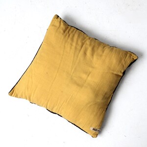 May include: A yellow throw pillow with a black border and a small "MADE IN" label on the bottom right corner.