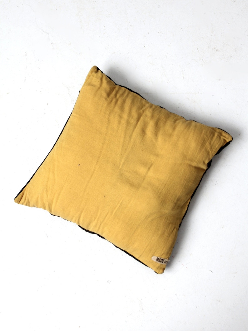 May include: A yellow throw pillow with a black border and a small "MADE IN" label on the bottom right corner.