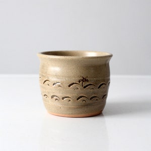 Peut inclure: Une tasse en céramique beige avec un motif brun de vagues et un palmier. La tasse a une surface légèrement texturée.