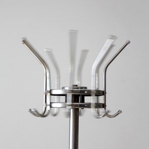 May include: A silver rotating coat rack with multiple hooks. The rack is made of metal and has a circular base.