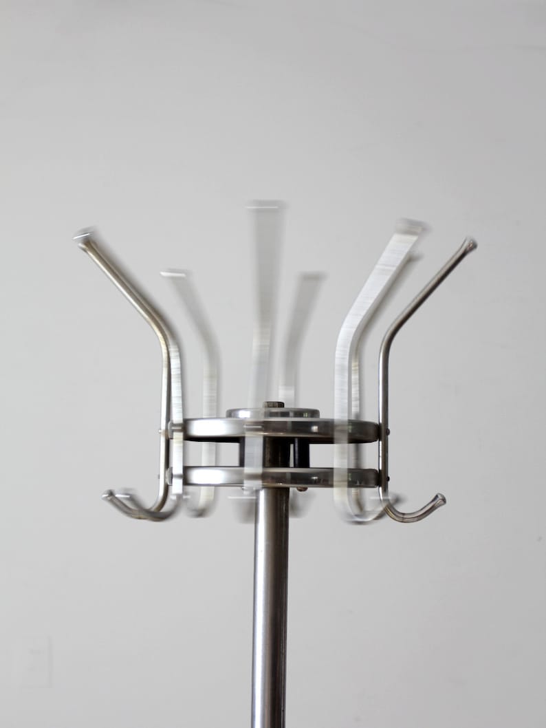 May include: A silver rotating coat rack with multiple hooks. The rack is made of metal and has a circular base.