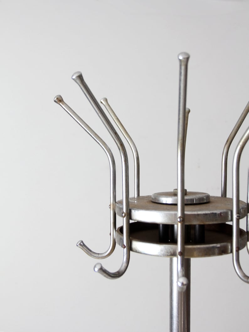 May include: A silver metal coat rack with multiple hooks. The rack has a round base and a tall, slender pole.