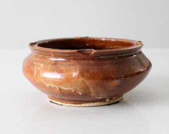 May include: A brown ceramic bowl with a slightly rounded rim and a glazed finish. The bowl has a rustic, handmade look.