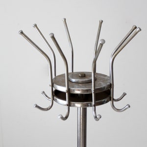 May include: A silver metal coat rack with a round base and multiple hooks. The hooks are arranged in a circular pattern around the base.