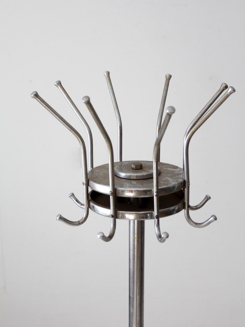 May include: A silver metal coat rack with a round base and multiple hooks. The hooks are arranged in a circular pattern around the base.