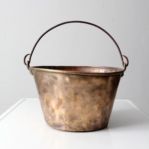 Può includere: Un secchio in ottone vintage con manico in filo metallico. Il secchio ha una patina usurata e invecchiata ed è perfetto per un arredamento rustico o da fattoria.
