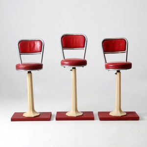 May include: Three red and silver vintage diner stools with white bases and red footrests.