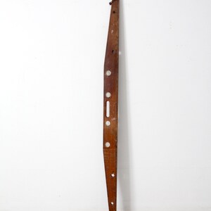 May include: A vintage wooden level with five circular bubble vials. The level is brown and has a slight curve to it. It is approximately 36 inches long.