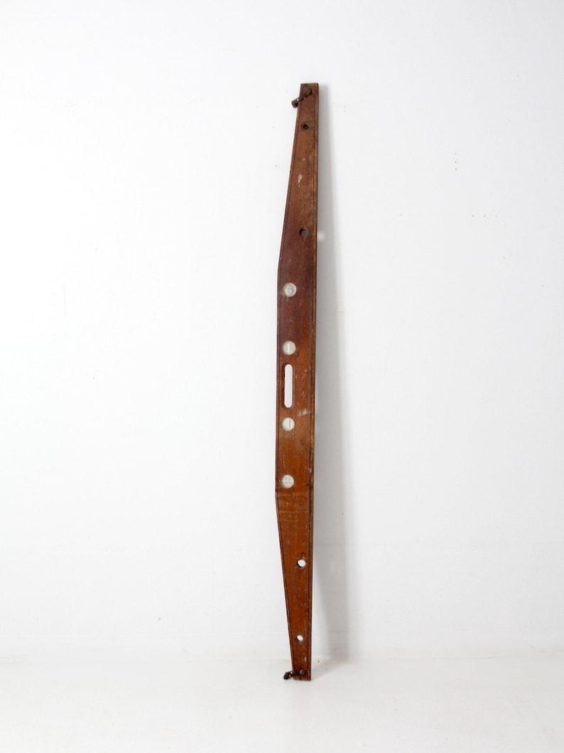 May include: A vintage wooden level with five circular bubble vials. The level is brown and has a slight curve to it. It is approximately 36 inches long.