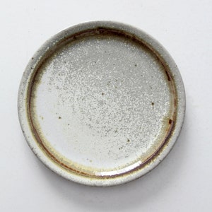 May include: A white ceramic plate with a brown rim. The plate has a speckled glaze and a rustic look.