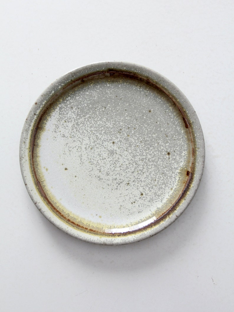 May include: A white ceramic plate with a brown rim. The plate has a speckled glaze and a rustic look.