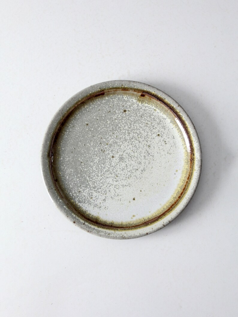 May include: A white ceramic plate with a brown rim. The plate has a speckled glaze and a rustic look.