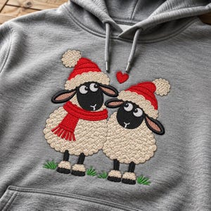 May include: A heather gray hooded sweatshirt featuring an embroidered design of two sheep with black faces and cream-colored wool. Both sheep wear red Santa hats with white pom-poms, and one sheep wears a red scarf. A small red heart is embroidered above them.