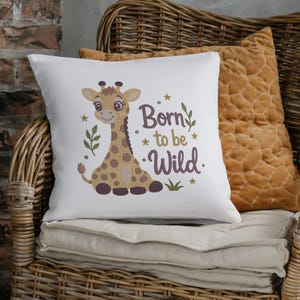 May include: A white square throw pillow featuring a brown giraffe illustration with dark brown spots. The text Born to be Wild is printed in dark brown script next to the giraffe, accompanied by small green leaf sprigs and gold stars.