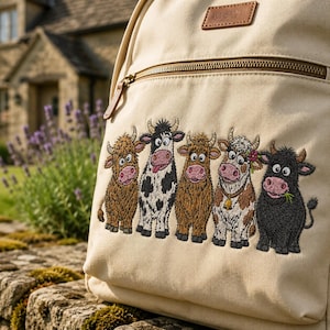 May include: A beige canvas backpack featuring an embroidered design of five cartoon cows in various colors and patterns. The backpack includes a front zippered pocket with a brown leather-like brand patch at the top and a metal zipper pull.