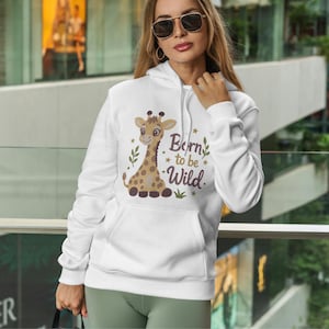 May include: A white hooded sweatshirt featuring a graphic of a brown spotted giraffe. The text "Born to be Wild" is printed in dark brown script next to the giraffe, accompanied by small gold star icons and green leaf illustrations.