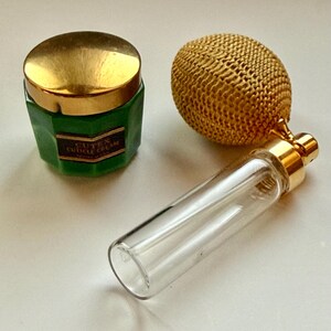May include: A vintage beauty set featuring a green Cutex Cuticle Cream jar with a gold lid, a gold-toned perfume atomizer, and a clear glass perfume bottle with a gold cap. The items are arranged on a white surface.