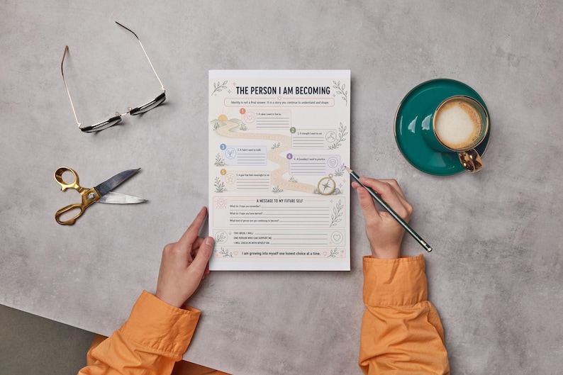 May include: A white paper worksheet titled THE PERSON I AM BECOMING with a winding path graphic, numbered prompts, and a section for a message to a future self. The sheet is surrounded by black-rimmed glasses, gold scissors, and a teal coffee cup.