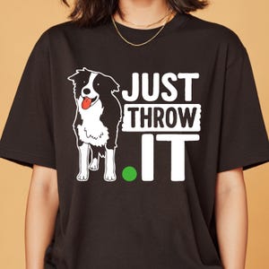 Może przedstawiać: Czarny t-shirt z czarno-białą ilustracją psa Border Collie i napisem "JUST THROW IT" w kolorze białym. Obecna jest również zielona kropka. Koszulka jest w stylu casual.