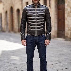 Könnte beinhalten: Eine schwarze Lederjacke mit Stehkragen, silberfarbenen Knöpfen im Militärstil und horizontalen hellgrauen Paspeln auf der Brust. Die Jacke wird mit einer dunkelblauen Jeans und schwarzen Lederstiefeln kombiniert, was einen strukturierten Look ergibt.