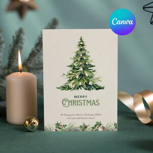 May include: A Christmas card featuring a watercolour illustration of a green Christmas tree, the words "MERRY CHRISTMAS", and festive greenery. Lit candles, a gold bell, and a ribbon are in the background.