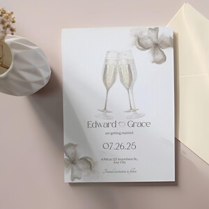 May include: A wedding invitation featuring champagne glasses and floral designs. The text reads "Edward & Grace are getting married 07.26.25 4 PM at 123 Anywhere St., Any City Formal invitation to follow."