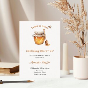 May include: Bridal shower invitation featuring a watercolour illustration of a honey jar and dipper. The text reads "Sweet as Honey" and "Celebrating Before 'I Do'" with event details for Amelia Taylor on 15th December 2026.