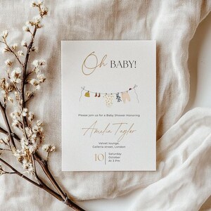 May include: A baby shower invitation with the words "Oh BABY!" in gold script. The invitation includes the name "Amelia Taylor" and details for the event, including the date, time, and location in London. A clothesline with baby clothes is illustrated.
