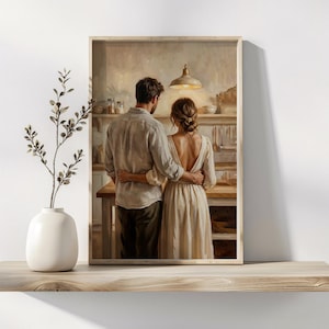 May include: A framed print showing a couple embracing in a kitchen. The man wears a light shirt and dark trousers, the woman a cream dress. The kitchen has a warm atmosphere, with a hanging light fixture and wooden surfaces.