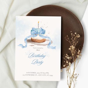 May include: A birthday party invitation with a watercolour illustration of a cupcake adorned with a blue ribbon and a lit candle. The invitation text reads "You're invited to Alex's Birthday Party" with date, time, and address details.