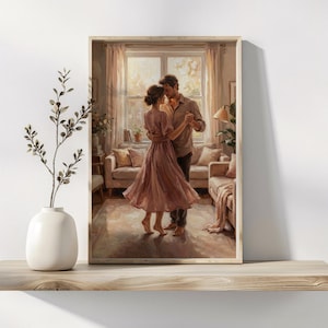 May include: A framed art print shows a couple dancing in a sunlit living room. The woman is in a flowing pink dress, and the man wears a button-down shirt. The room features a window, curtains, and furniture in warm tones.