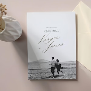 May include: A white wedding invitation featuring a monochrome photograph of a couple running. The text reads "Save the Date", the date "23.07.2027", and the names "Karyen + James" in a script font.