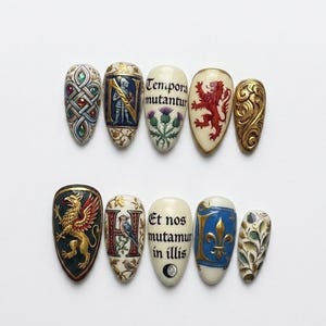May include: A set of ten intricately designed artificial nails. Each nail features unique artwork, including heraldic symbols, floral patterns, and Latin phrases. Colors include gold, red, blue, green, and white, with detailed miniature paintings.