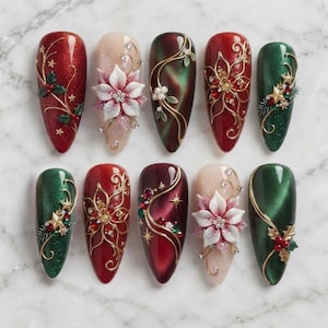 May include: Ten almond-shaped press-on nails featuring holiday designs. The set includes deep red, forest green, and nude base colors with gold filigree, 3D white poinsettia flowers, red berries, green pine needles, and gold star accents.