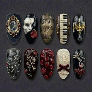 May include: A set of ten artificial nails with various designs. The designs include a broken mirror, a Phantom of the Opera mask, musical notes, a piano keyboard, a chandelier, and other ornate elements. The nails are oval-shaped and painted in dark colors.