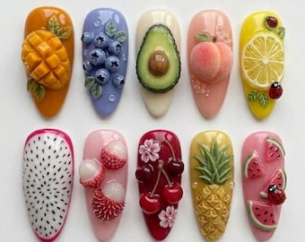 May include: A collection of ten artificial nails, each uniquely designed with 3D fruit embellishments. The designs include a mango, blueberries, avocado, peach, lemon, dragon fruit, lychee, cherries, pineapple, and watermelon. Each nail is painted in a different color.
