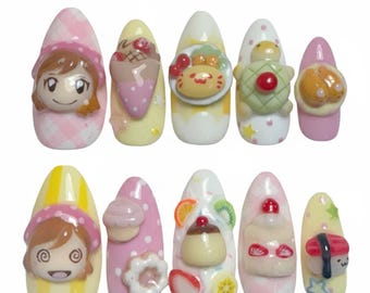 May include: A set of ten artificial nails, each uniquely decorated with 3D designs. The designs include cartoon characters, desserts, and sushi, in a variety of colors including pink, yellow, and white. Some nails feature polka dots and star accents.