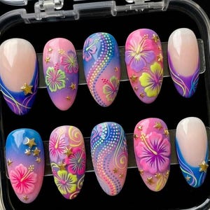 May include: A set of ten artificial nails with a tropical theme. Each nail features a different design, including hibiscus flowers, stars, and gradient colors of pink, purple, blue, and yellow. The nails are oval-shaped and have a glossy finish.
