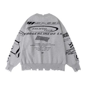 May include: A gray crew neck sweater with distressed edges. The back features black text and graphics, including "SPEED", "EZLIFOO CLUB", and a checkered flag design. The text reads "YOUNG YOU HAVE COUNTLESS OPPORTUNITIES TO TRY..."