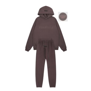 May include: A brown hoodie and matching sweatpants set. The hoodie features the word "ESSENTIALS" across the chest. The drawstring sweatpants have a matching drawstring. The set is made of a soft material.