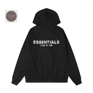 May include: Black hoodie with the word "ESSENTIALS" printed in white across the back, with "FEAR OF GOD" below it. The hoodie has a hood and long sleeves. The brand logo is in the upper left corner.