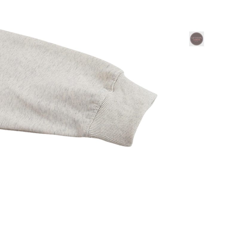 May include: Close-up of a light gray sweatshirt sleeve. The cuff is ribbed and a slightly darker shade of gray. The fabric has a flecked texture. The sleeve is angled towards the bottom right corner of the image.