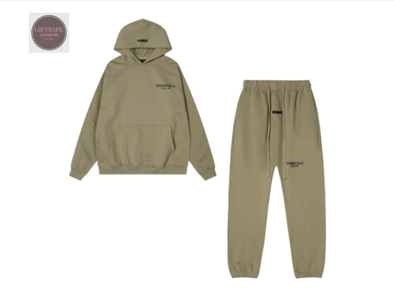 May include: A matching olive green hoodie and sweatpants set. The hoodie has a hood, a front pocket, and the word "ESSENTIALS" printed on the chest. The sweatpants have a drawstring waist and the word "ESSENTIALS" printed on the leg.
