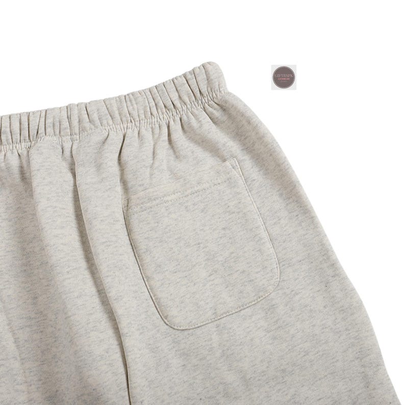 K&ouml;nnte beinhalten: Nahaufnahme von hellgrauen Sweatshorts mit elastischem Bund und einer einzelnen Ges&auml;&szlig;tasche. Die Shorts bestehen aus einem weichen, bequemen Material, ideal f&uuml;r Freizeitkleidung. Die Shorts haben eine neutrale Farbe.