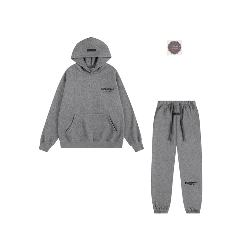 K&ouml;nnte beinhalten: Ein graues Hoodie- und Jogginghosen-Set. Der Hoodie hat eine Vordertasche und das Wort "ESSENTIALS" auf der Brust aufgedruckt. Die Jogginghose hat einen Kordelzug in der Taille und das Wort "ESSENTIALS" auf dem Bein aufgedruckt. Das Set ist aus weichem Material.