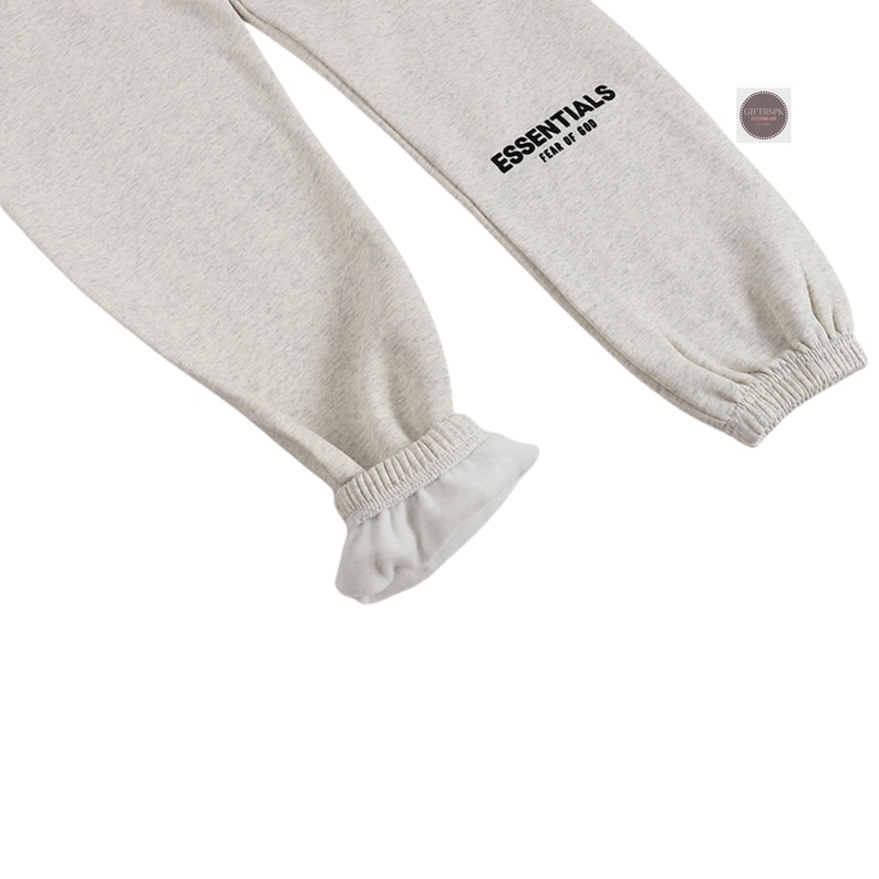 K&ouml;nnte beinhalten: Hellgraue Jogginghose mit elastischen B&uuml;ndchen und dem Wort "ESSENTIALS" in Schwarz auf dem Bein aufgedruckt. Die Hose ist aus einem weichen, bequemen Material gefertigt.