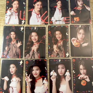 Pode incluir: Um conjunto de cartas colecionáveis com tema de Halloween. As cartas apresentam indivíduos fantasiados, com adereços como chifres de diabo, forcados e sacos de guloseimas em forma de abóbora. As cartas têm uma borda preta com decorações de Halloween.