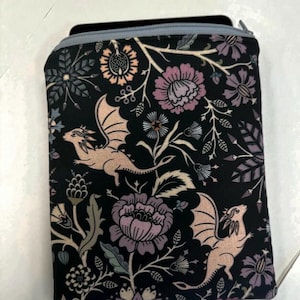 Könnte beinhalten: Schwarze Tasche mit Reißverschluss und floralem Muster mit Drachen. Die Tasche ist mit grauem Stoff gefüttert und hat einen Reißverschluss.