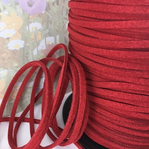 May include: A spool of red suede cord, wound tightly and ready to be used for crafting projects.