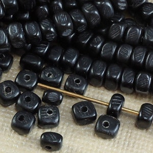 May include: Black square beads with a textured surface. The beads are strung on a gold wire.